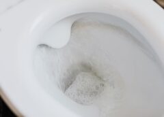flushing water in white toilet bowl
