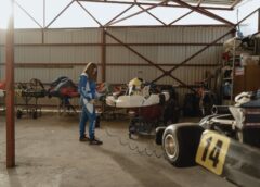 woman in racing suit checking her go kart in the garage
