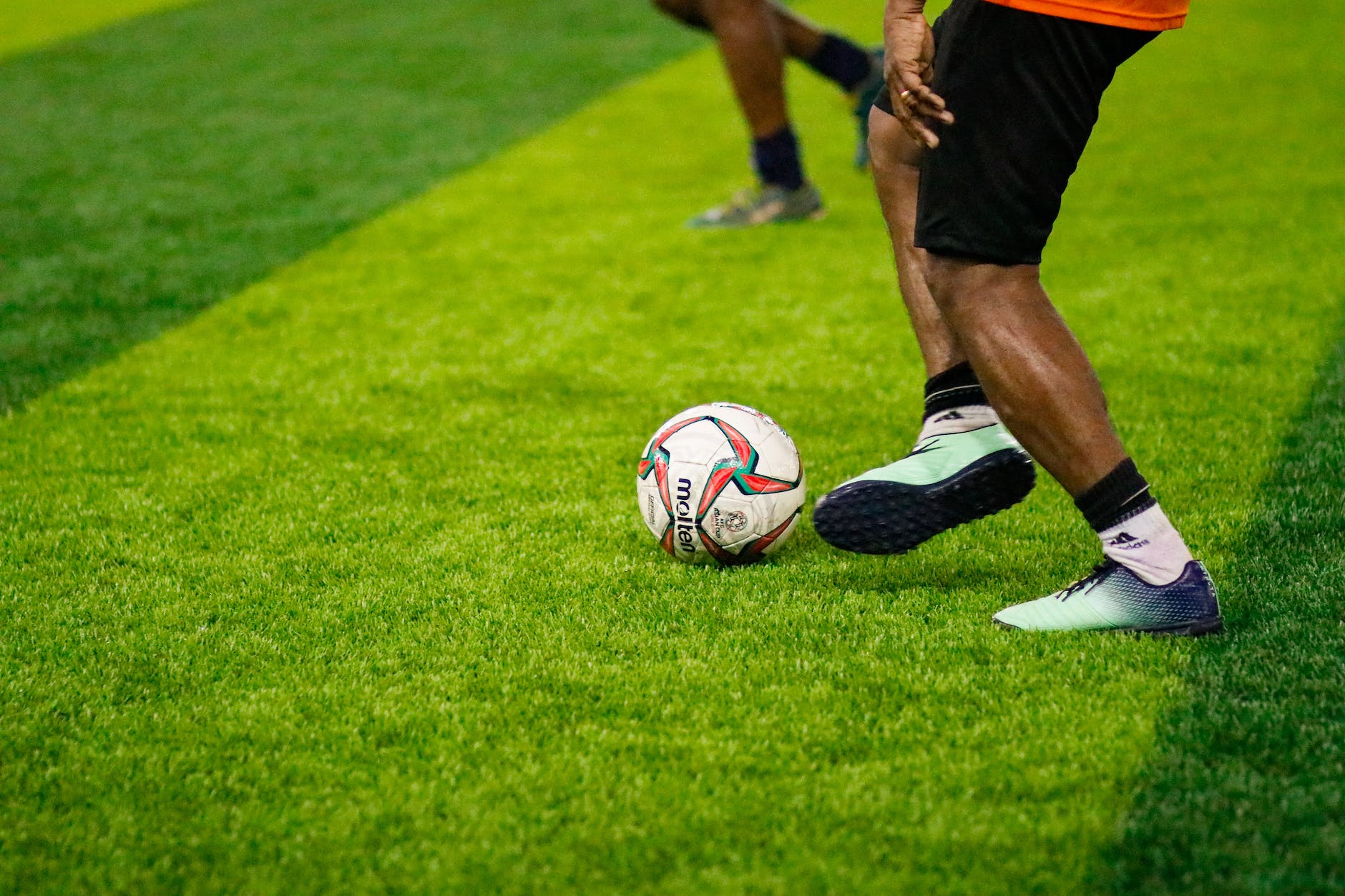closeup of a footballer kicking a ball on a green lawn