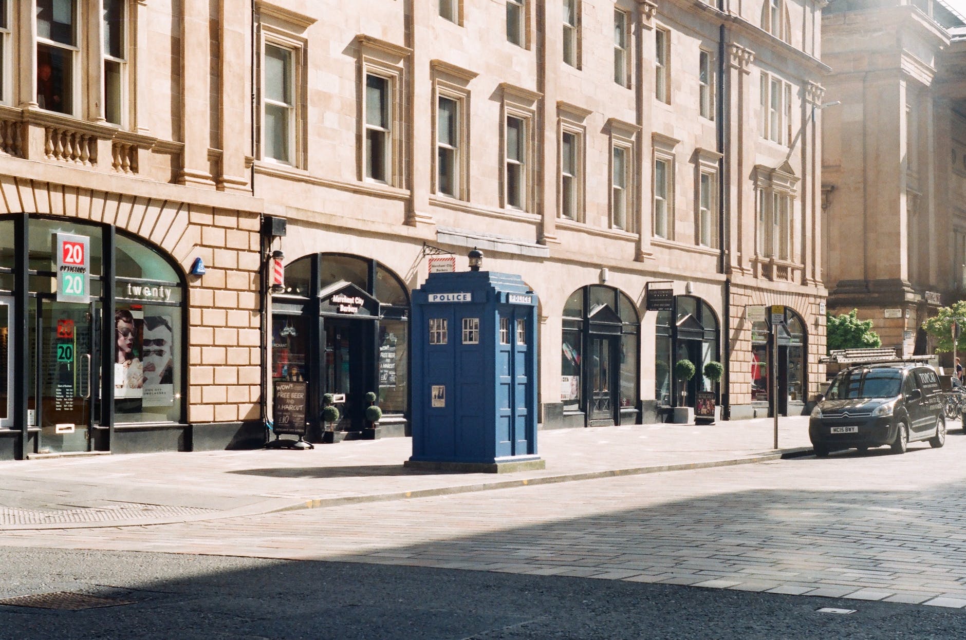 photo of a street and a blue police box against the background of a beige facade of a building